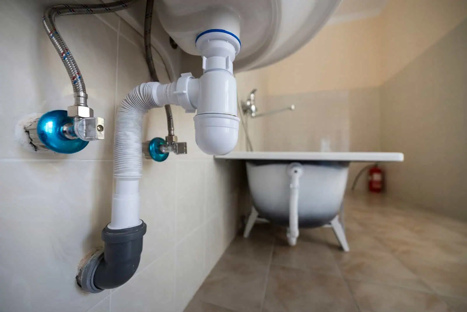 Plumbing pipes and drain under sink in bathroom for water damage restoration.
